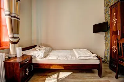 a small bedroom with a bed and a dresser at Noclegi Styrnol & SPA in Zawoja