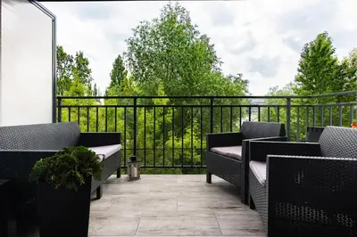 a balcony with chairs and a black fence at Zlota Jesien apartment by NEARTO PL in Kraków