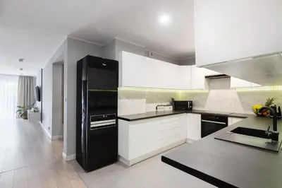 a kitchen with a black refrigerator and white cabinets at Zlota Jesien apartment by NEARTO PL in Kraków