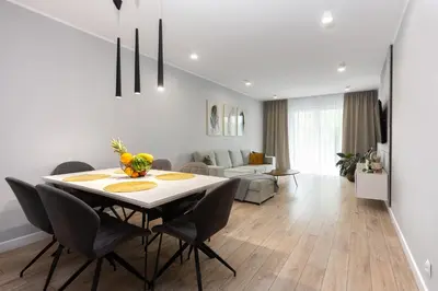 a dining room and living room with a table and chairs at Zlota Jesien apartment by NEARTO PL in Kraków