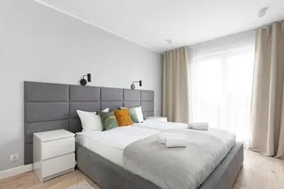 a bedroom with a large bed with a large window at Zlota Jesien apartment by NEARTO PL in Kraków