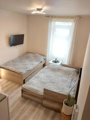 two beds in a room with a tv on the wall at Studio near Old Town in Kraków