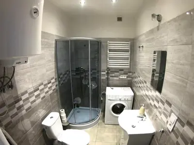 a bathroom with a shower sink and a washing machine at Studio near Old Town in Kraków