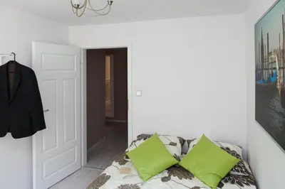 a white room with a couch with green pillows at Kraków Cosy 3 room 2 bathroom Old Town in Kraków