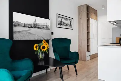 a living room with a table and two green chairs at HOUSEHOST Apartments: Miodowa 42/12b Street in Kraków