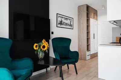 a living room with a table and two green chairs at HOUSEHOST Apartments: Miodowa 42/12b Street in Kraków