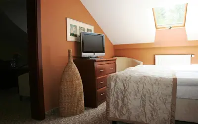 a bedroom with a bed and a television on a dresser at Centuria Hotel & Natural Spa in Ogrodzieniec