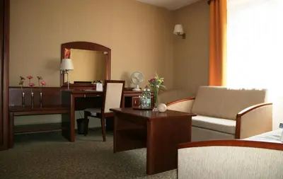 a living room with a desk and a living room with a couch at Centuria Hotel & Natural Spa in Ogrodzieniec