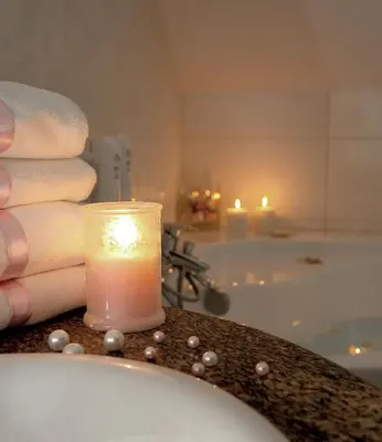 a candle sitting on a counter next to a bath tub at Centuria Hotel & Natural Spa in Ogrodzieniec