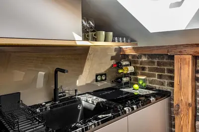 a kitchen with a sink and a brick wall at Skyline by MB Apartments in Kraków