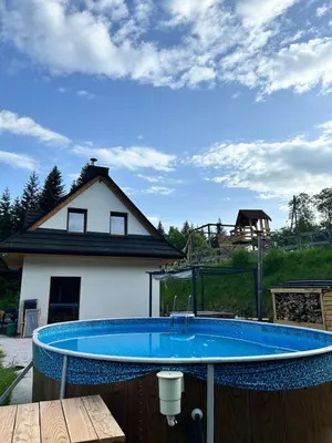 a large blue swimming pool in front of a house at Zawoja Domki z Jacuzzi in Zawoja