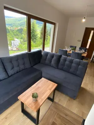a living room with a blue couch and a table at Zawoja Domki z Jacuzzi in Zawoja