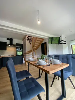 a dining room and kitchen with a wooden table and blue chairs at Zawoja Domki z Jacuzzi in Zawoja