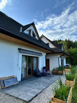 a white house with a patio in front of it at Zawoja Domki z Jacuzzi in Zawoja