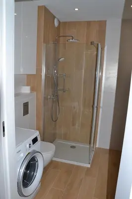 a bathroom with a shower with a toilet and a washer at Apartament Krakusek Kraków in Kraków