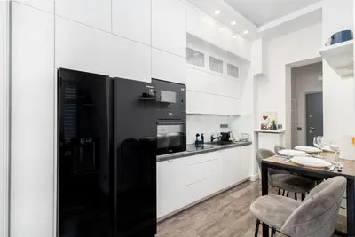 a black refrigerator in a white kitchen with a table at Malila Premium Apartments Cracow Centre Starowiślna 43 in Kraków