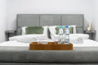 a tray with bottles of water and glasses on a bed at Malila Premium Apartments Cracow Centre Starowiślna 43 in Kraków