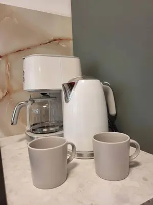 a coffee maker and two cups on a counter at Mieszkanie na Starym Podgórzu. in Kraków