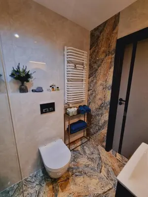 a bathroom with a toilet and a stone wall at Apartament Jacuzzi in Kraków