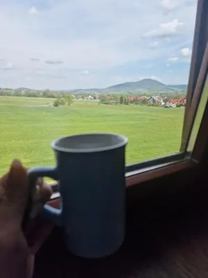 a person holding a coffee cup in front of a window at Dom w górach in Lipnik