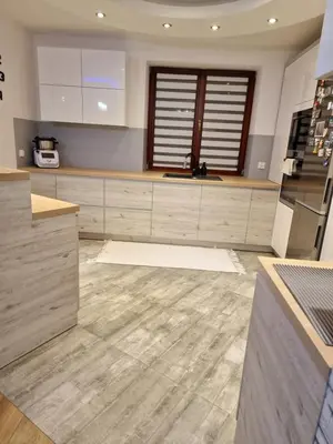 a kitchen with white cabinets and a wooden floor at Dom w górach in Lipnik