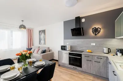 a kitchen and living room with a table and chairs at Dabie Park Residence in Kraków