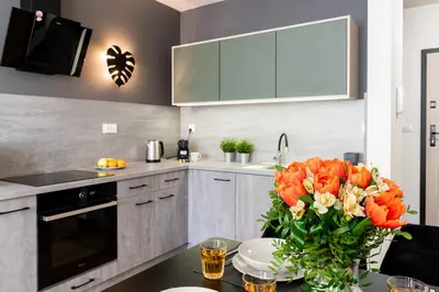 a kitchen with a table with a vase of orange flowers at Dabie Park Residence in Kraków