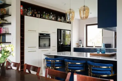 a kitchen with a bar with blue chairs at Granatowy Dom in Stary Wiśnicz