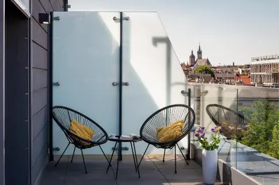 a patio with three chairs and a table on a balcony at InPoint Wawel View Apartments- Free Underground Parking in Kraków