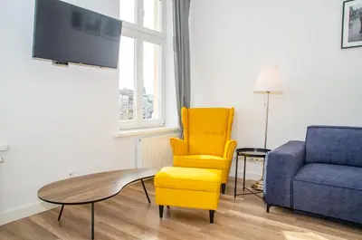 a living room with a yellow chair and a blue couch at InPoint Wielopole 32 Boutique Apartments Old Town&Kazimierz District Self Check-in in Kraków