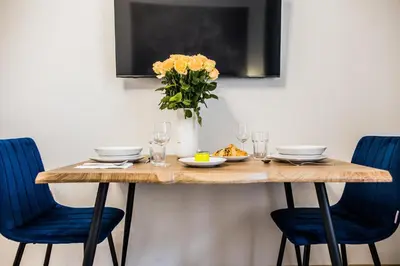 a dining room table with blue chairs and a vase of flowers at CracWoW K8 Apartments in Kraków