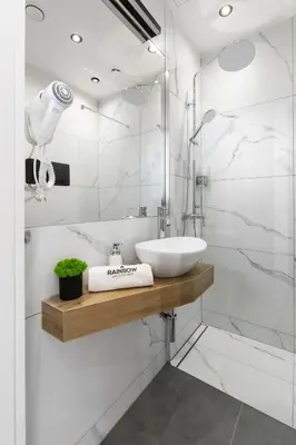 a white bathroom with a sink and a shower at Rainbow Apartments Old Town in Kraków