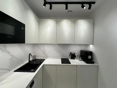 a white kitchen with a sink and a microwave at Rainbow Apartments Old Town in Kraków