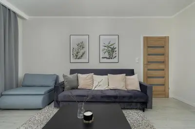 a living room with a blue couch and a table at Home Office - 2-Bedroom Apartment Corpo-Stay in Kraków by Noclegi Renters in Kraków