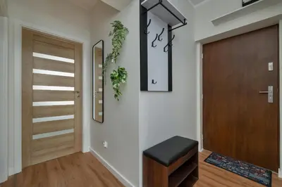 a hallway with a wooden door and a stool at Home Office - 2-Bedroom Apartment Corpo-Stay in Kraków by Noclegi Renters in Kraków