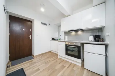 a kitchen with white cabinets and a wooden door at Apart-Studio Close Wawel Castle in Kraków