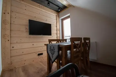 a dining room with a table and a television on a wall at Cyrhel Apartments in Zawoja