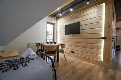 a bedroom with a bed and a table and a tv at Cyrhel Apartments in Zawoja