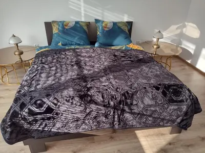 a bed with a black blanket on top of it at La Casa De Roland in Wieliczka