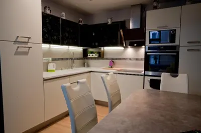 a kitchen with white cabinets and a table and chairs at Magic Apartment in Kraków
