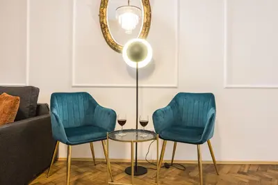 two blue chairs and a table with two glasses of wine at CracWoW K8 No.1 Apartment in Kraków