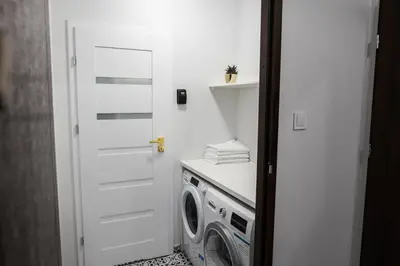 a laundry room with a white door and a washing machine at CracWoW K8 No.2 Apartment in Kraków