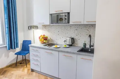 a kitchen with white cabinets and a blue chair at CracWoW K8 No.8 Apartment in Kraków