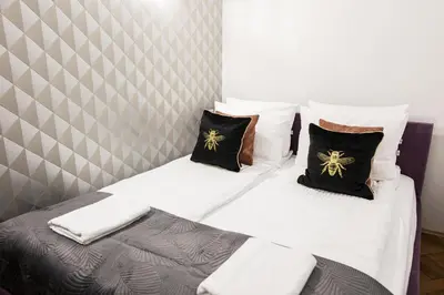 a bedroom with two beds with white sheets and black pillows at CracWoW K8 No.8 Apartment in Kraków