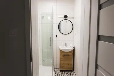 a white bathroom with a sink and a mirror at CracWoW K8 No.10 Apartment in Kraków