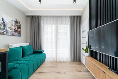 a living room with a green couch and a large television at Krakowiak Apartment 65 in Kraków