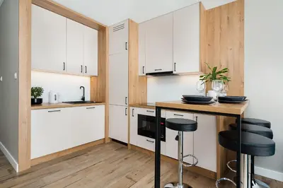 a kitchen with white cabinets and a counter with stools at Krakowiak Apartment 65 in Kraków