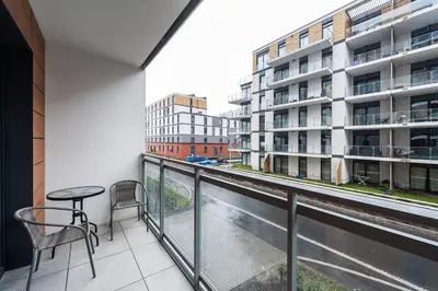 a balcony with a table and chairs and a view of a street at Krakowiak Apartment 65 in Kraków