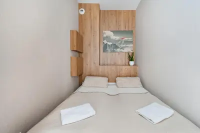 a small bedroom with a bed with white sheets at Krakowiak Apartment 65 in Kraków