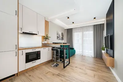 a kitchen with white cabinets and a table in a room at Krakowiak Apartment 65 in Kraków